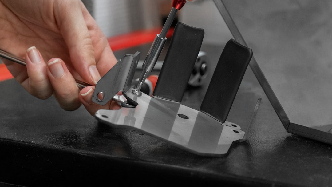 A person's hand adjusts a metal clamp on a surface.